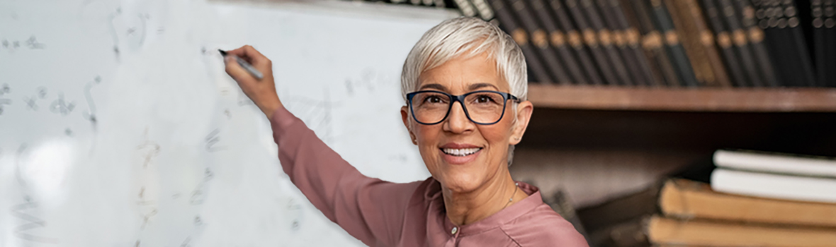 Professeur féminin debout devant un tableau blanc