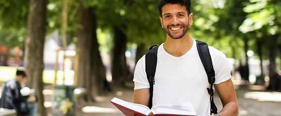 Male student holding a book and smiling